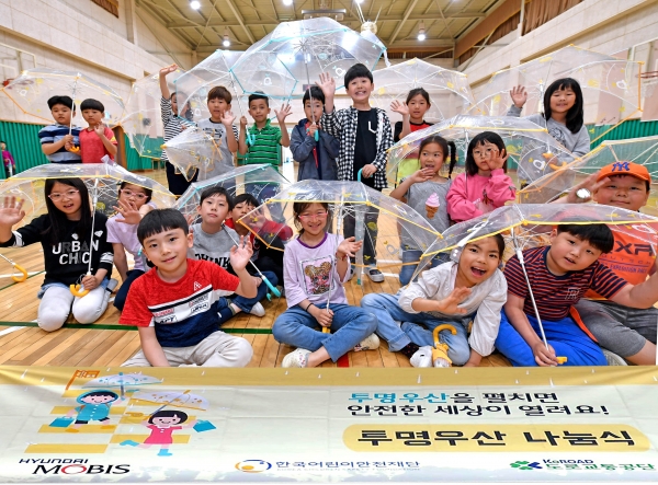 서울 고산초등학교 학생들이 현대모비스가 배포한 투명 우산을 들고 포즈를 취하고 있다. 현대모비스는 올해 학교 방문, 개인사연 신청 등을 통해 10만 개 이상의 투명 우산을 배포할 예정이다. 이에 따라 2010년부터 배포한 투명 우산은 올해 100만개를 돌파하게 된다. 사진=현대모비스 제공