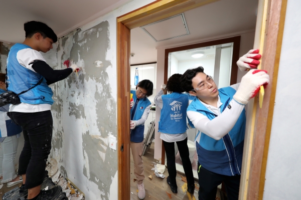 희망의 집 고치기 봉사활동에 나선 대우건설 직원들이 노후된 벽지를 제거하고 있다.